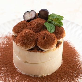 Close-up of a delicious tiramisu dessert topped with cocoa and garnish.