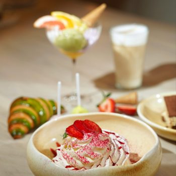 Elegant dessert presentation with strawberries, whipped cream, and a variety of sweets in a cozy setting.